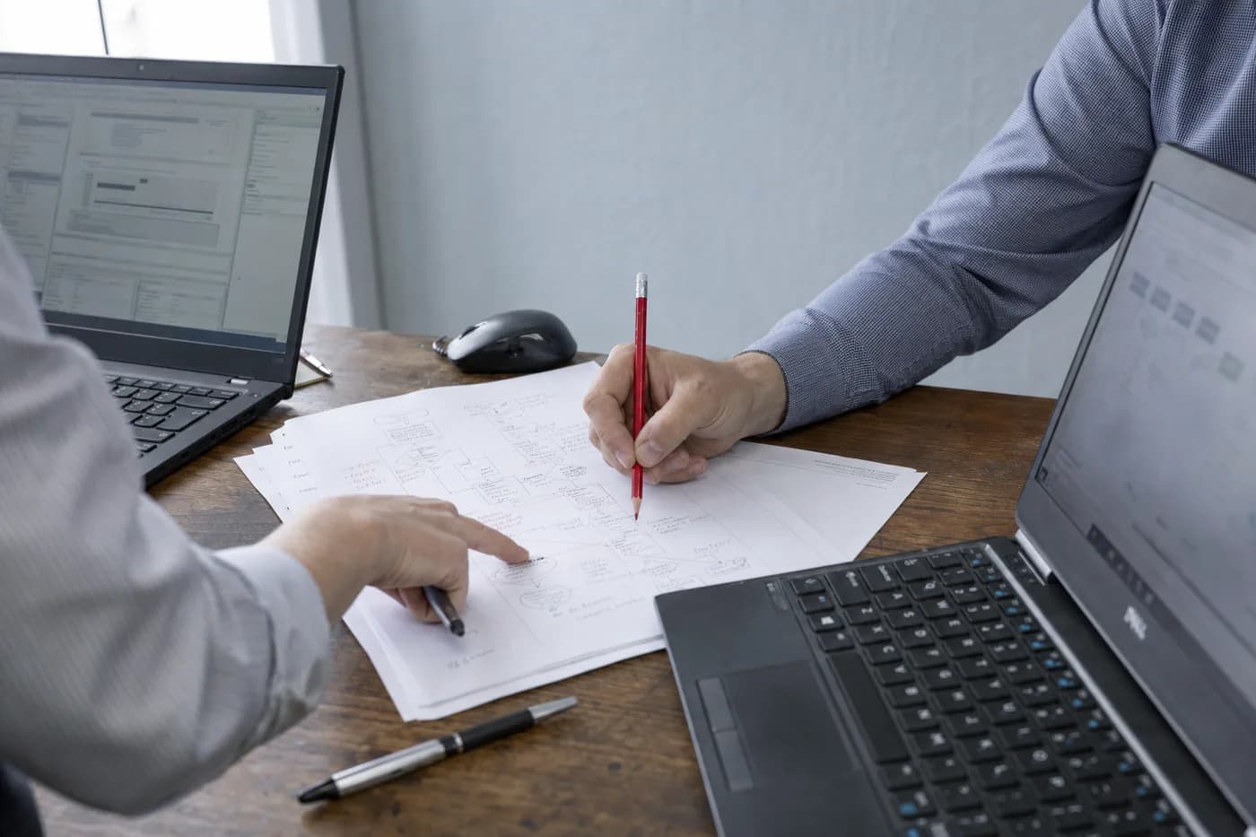 Working through a business's processes on paper, between two open laptops